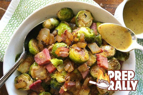 Roasted Brussels sprouts are shown mixed with chunks of ham and sauteed onions in a bowl. This is a quick and easy gluten free recipe.