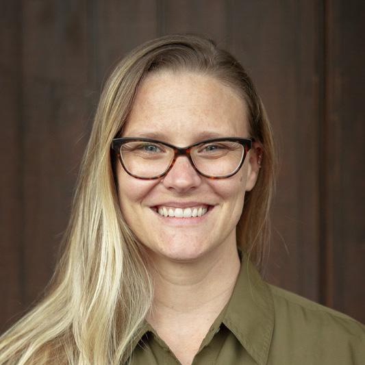 Brittany Hayes, Vice President of Sales at Pederson's Farms, stands smiling against a dark wood background.