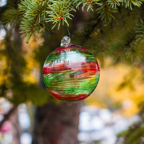 A round ornament, twisted with vibrant red, green, and gold inside. The texture of the crushed glass melted into it is visible, making it appear luscious and complex.