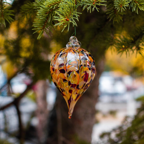 Finally, a finial ornament, rounded at the top and tapered into a point at the bottom. Using a mix of reds, browns, and blacks and an optic mold, this ornament reminds the viewer of the unique patterns of wildlife.