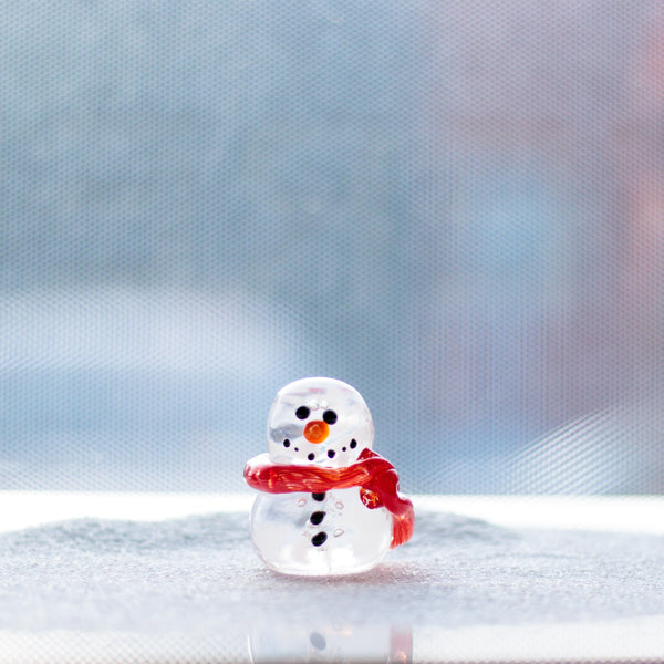 A clear solid glass snowman with a bright red scarf.