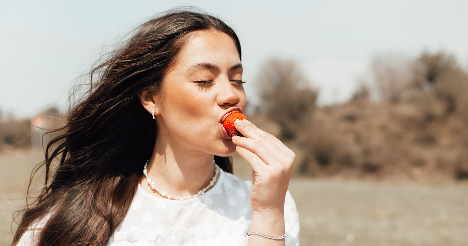 Woman is happily enjoying a strawberry