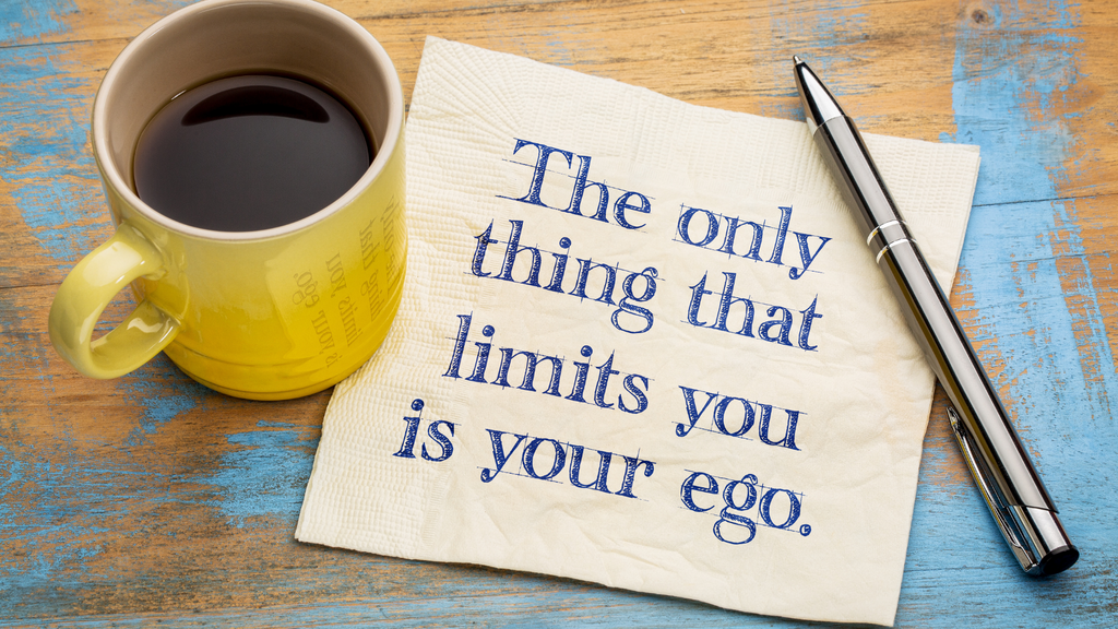 Note about curbing your ego on a table with coffee mug and pen
