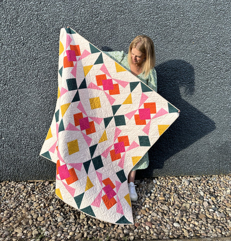 a white woman holding a pink quilt