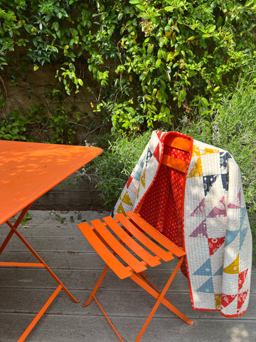 A quilted jacket hangs over the back of a garden chair