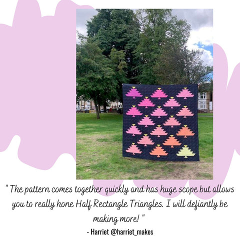a machine quilted throw size quilt top featuring ombre rows of pink trees displayed outdoors