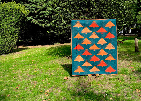 Green Nordmann quilt with autumn fir trees in orange on display in a park