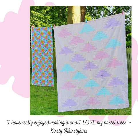 a pastel pink large quilt top featuring diagonal stripes  multi coloured pastel trees hanging on a washing line tees