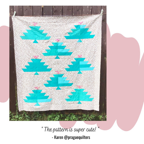 a baby sized quilt top featuring turquoise fir trees with link toppers against a gold printed ground