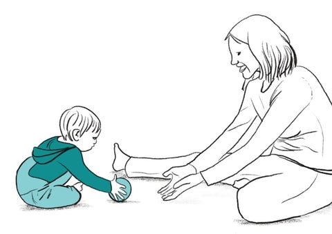 an adult is rolling a ball and playing with a baby