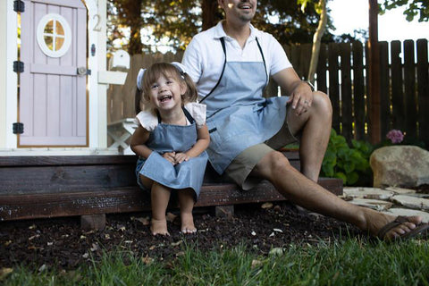 Child with her father sitting on the porch wearing aprons