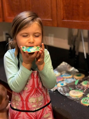 Girl eats a sugar cookie in a Splash Fabric apron