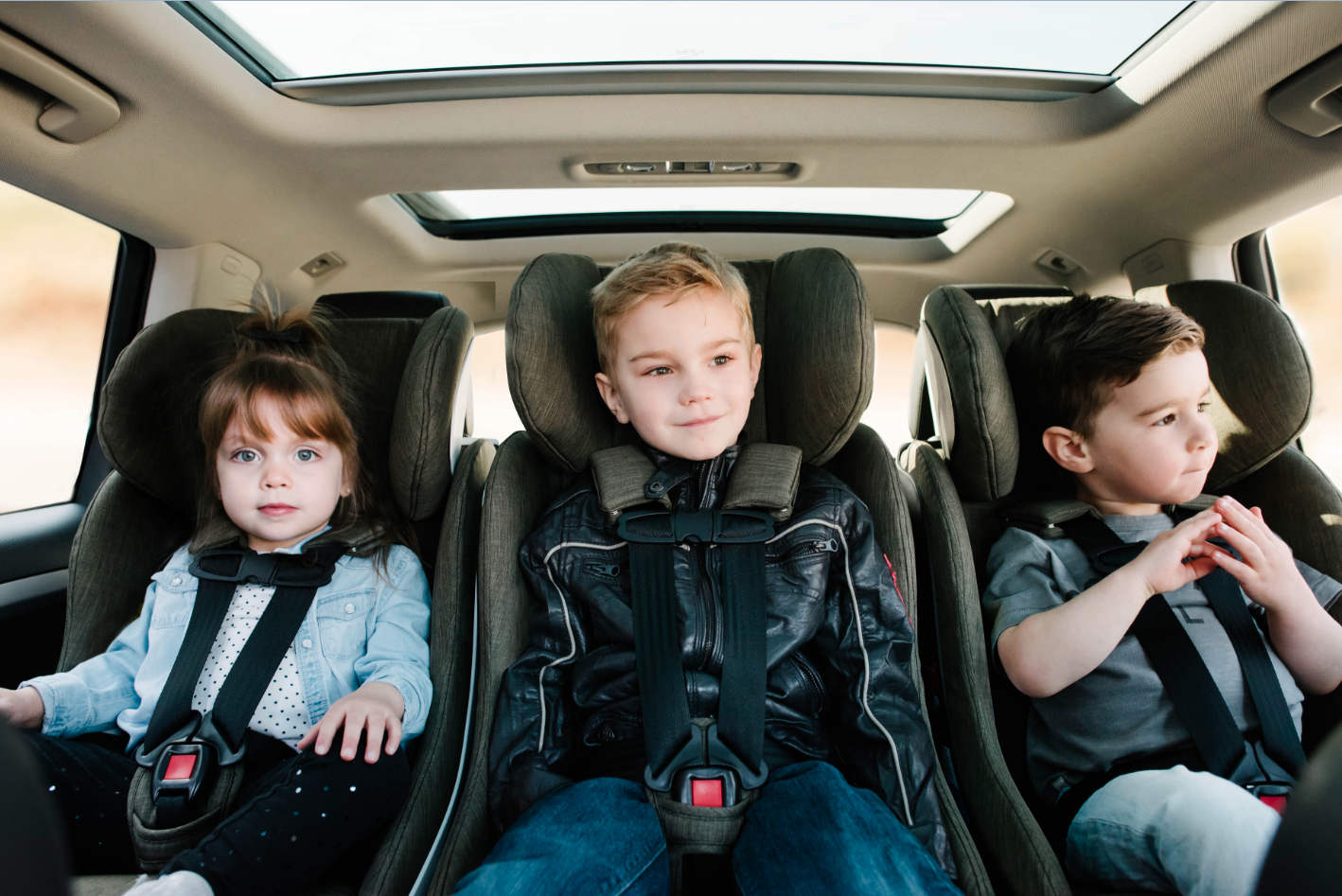 Children ride in 3 clek car seats across a vehicle seat back