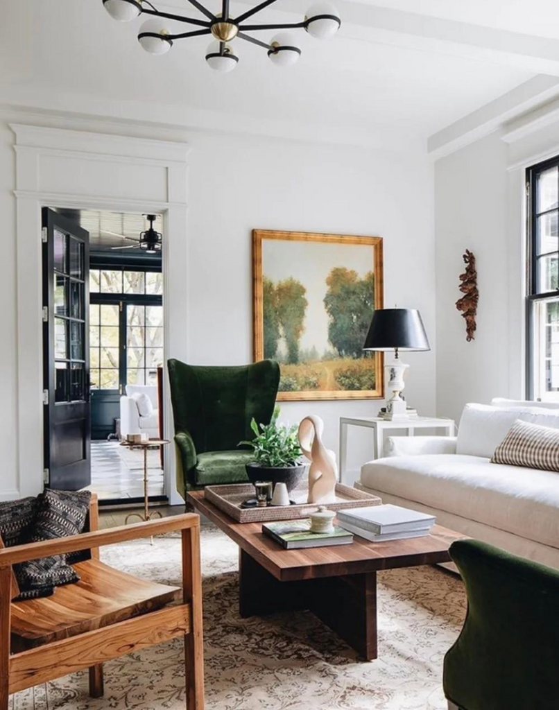 Mix styles and eras to create a collected home style. Living room scene with sofa, green velvet wingback chairs, wood accent chair and mixed style elements.