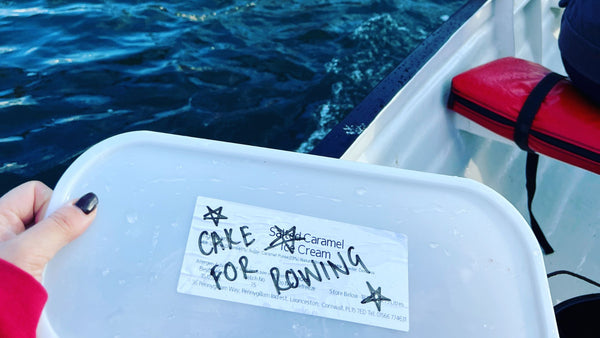 An icecream box on a gig boat, the box says cake for rowing on the lid