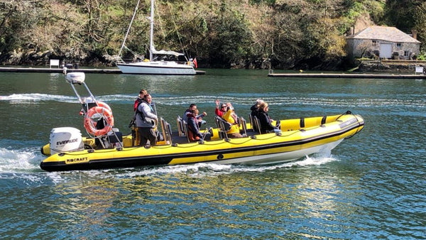 A yellow & black speedboat with 8 people on board on the Fowey estuary