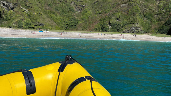 The view of Lantic Bay Cornwall from the water as seen from a yellow & black rib boat