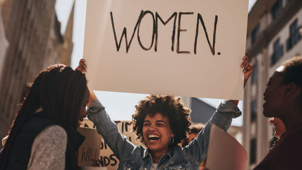 A woman holding a placard which says women