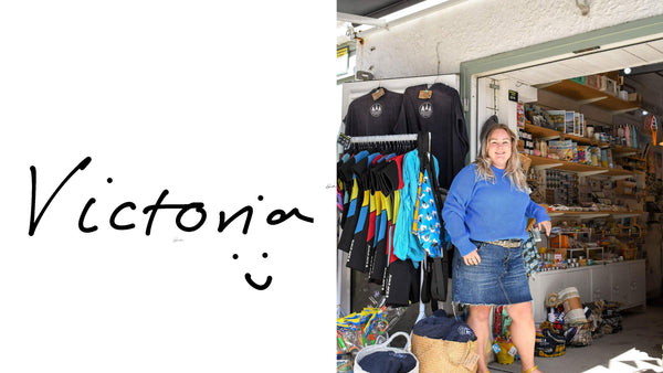 Victoria, owner of Readymoney Beach Shop, standing outside the shop on a sunny day. Victoria is smiling and wearing a blue jumper and short denim skirt