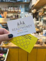 a hand holding two Readymoney Beach Shop loyalty cards