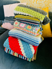 A stack of colourful crochet blankets made by Victoria