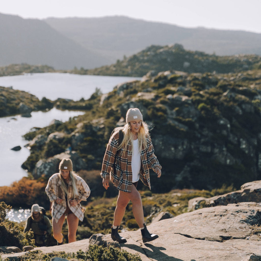 Group of adults wearing beanies hiking through Tasmania
