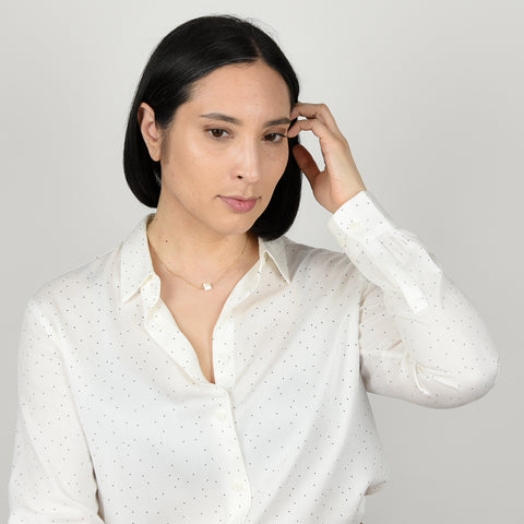 Model from waist up in while button down with small black polka dots, with straight, shoulder length hair wearing mystic peach moonstone necklace in 14K gold fill.