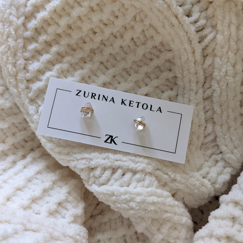 Zurina Ketola's herkimer diamond post earrings in 14K gold fill on an earring card, nestled on top of a white cable knit blanket. 