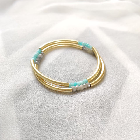 A pair of triplet bangles in amazonite and gray moonstone on ivory crepe silk. 