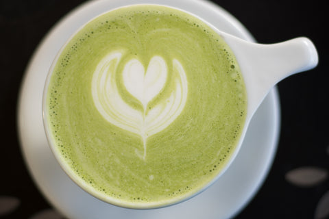 Overhead view of a beautiful green matcha latte in a white cup on a white saucer.