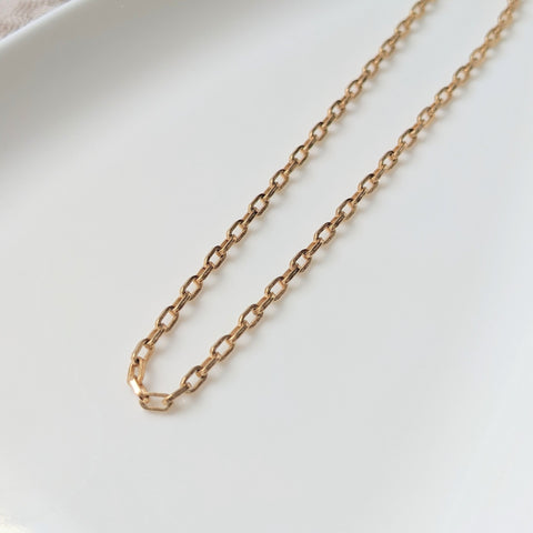 Zurina Ketola's Luxe Choker Necklace in 14K gold fill lays on top of a white ceramic plate and is angled to the right. 
