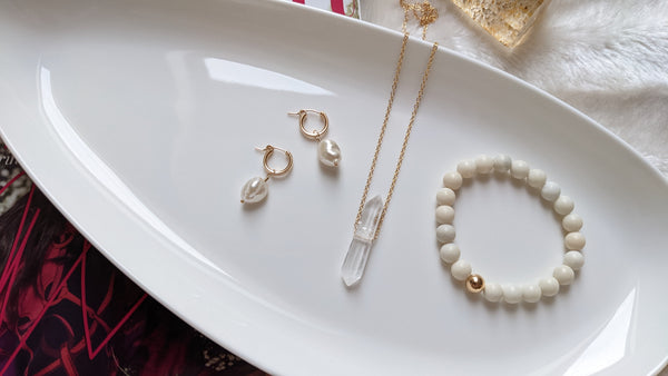 Jewelry flatlay image featuring aivory jade bracelet with gold details, crystal necklace, and pearl earrings