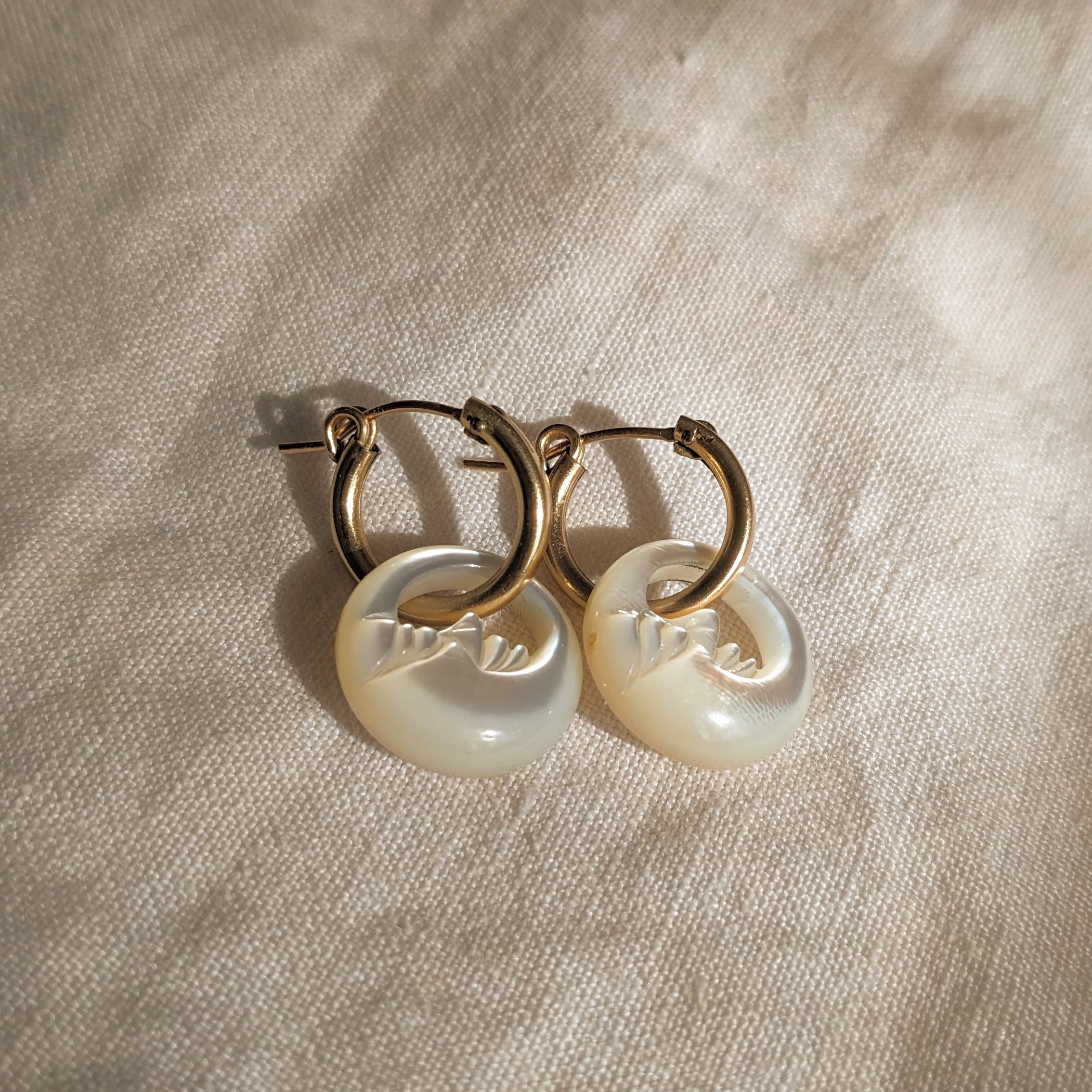 Overhead image of Zurina Ketola's golden Crescent Moon Huggie Hoops