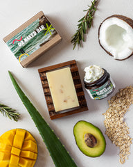 The 02 Naked Bar is featured in the center of the page. One of its main ingredients is colloidal oatmeal. Also featured is the 22 Naked Mango Butter and pictures of mango, aloe vera, avocado, coconut and colloidal oatmeal to visually show the ingredients in the soap bar. 