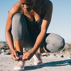 woman tying her shoes and preparing to go for a run