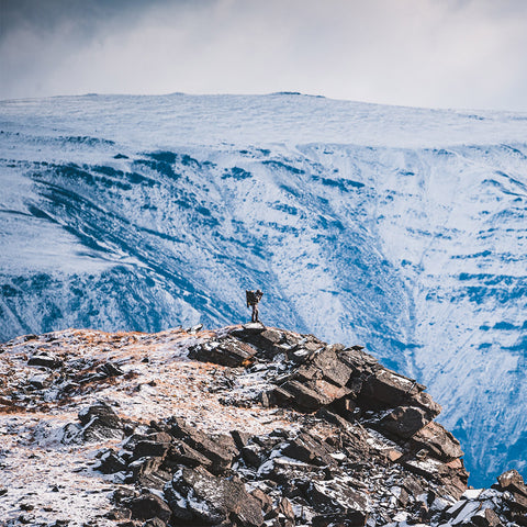 Man standing on mountain top taken from another mountain top, wearing Sitka Gear Kelvin Aerolite Pants, Jacket and Vest