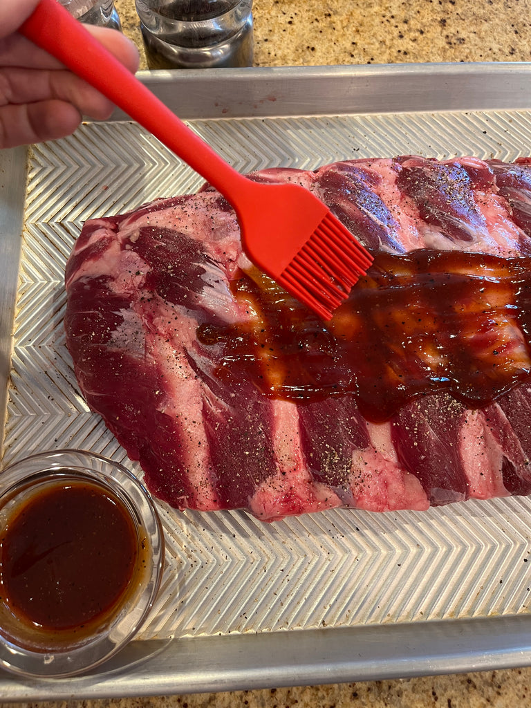 Bison ribs bring brushed with barbecue sauce before cooking