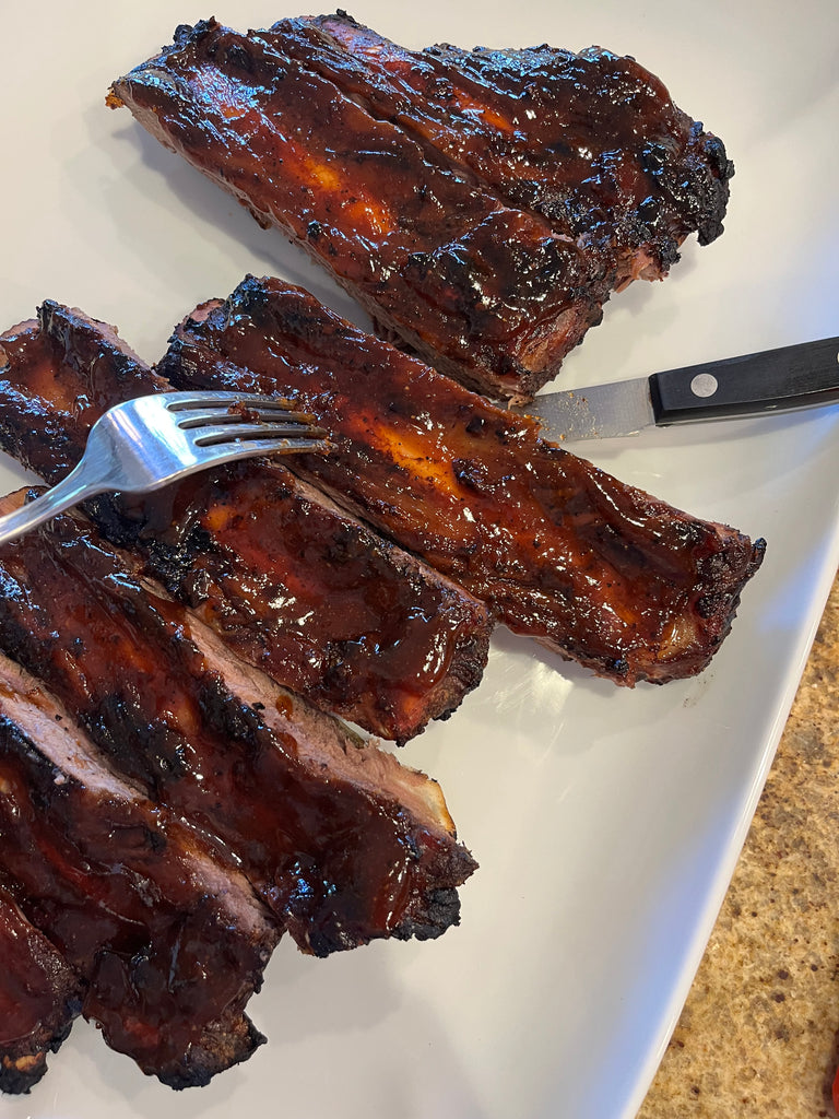 Cooked bison ribs on a platter with fork and spoon