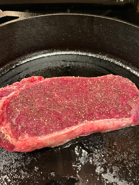 Bison ribeye steak in a cast iron pan