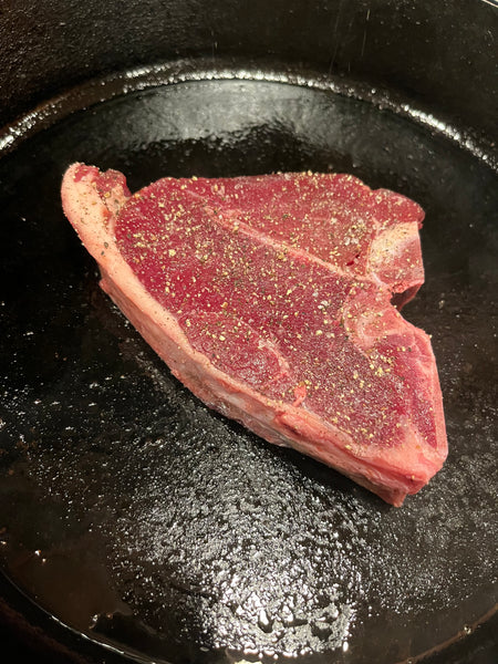 Elk porterhouse steak in a cast iron pan