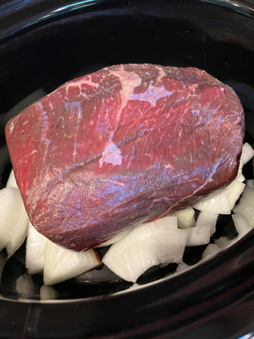 All Natural Angus Chuck Roast from Frontière Natural Meats in a crock pot with onions 