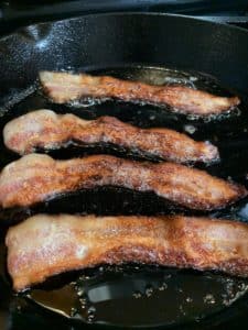 Strips of bacon sizzling in a skillet