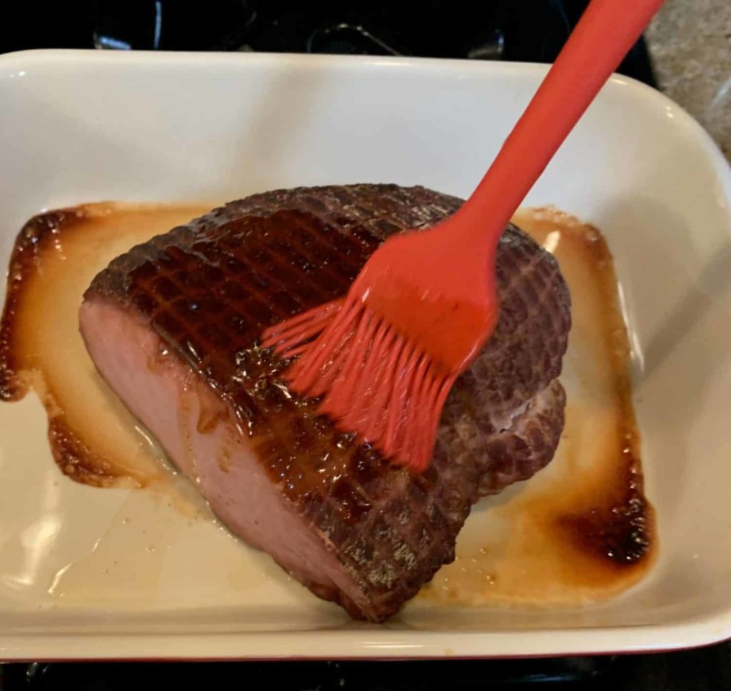 Glazing a ham with a basting brush