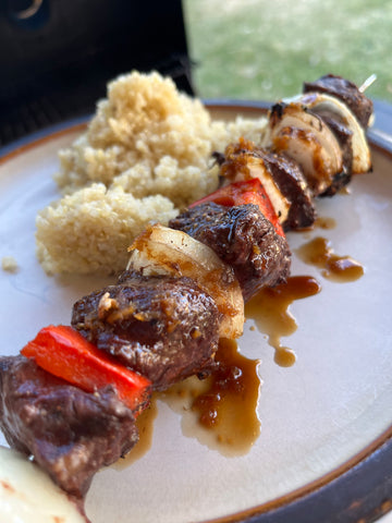 Grilled elk skewer on a plate with quinoa and ginger sauce