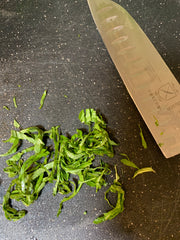 Chiffonade of basil on a cutting board with a knife