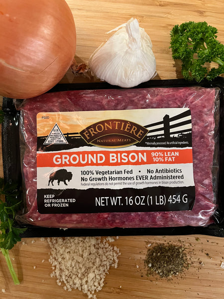 Bison meat on a cutting board with spices and vegetables