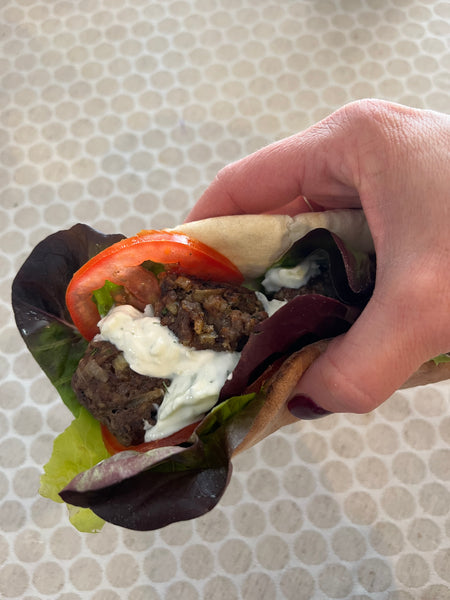 Hand holding a pita sandwich with gyro meatballs