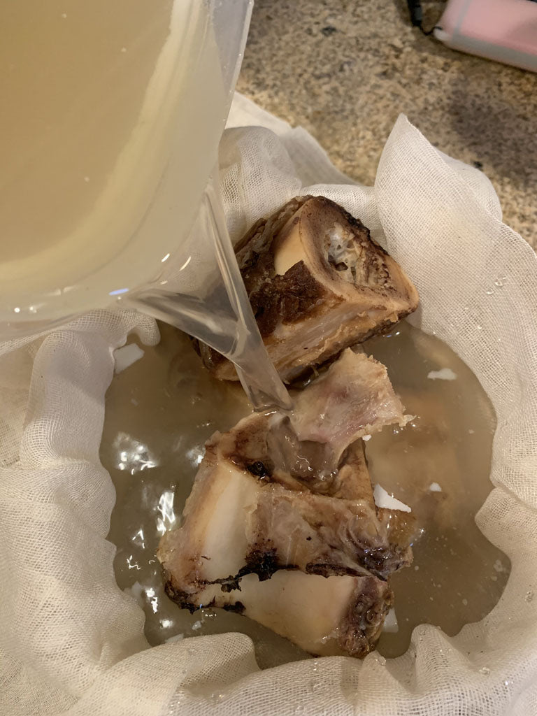 Pouring bone broth into cheese cloth