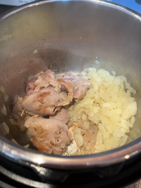 Chicken thighs browning in an Instant Pot with onions