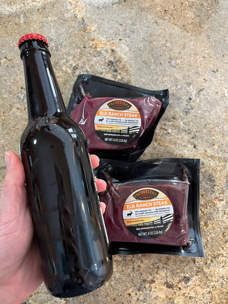 Bottle of beer next to two elk ranch steaks